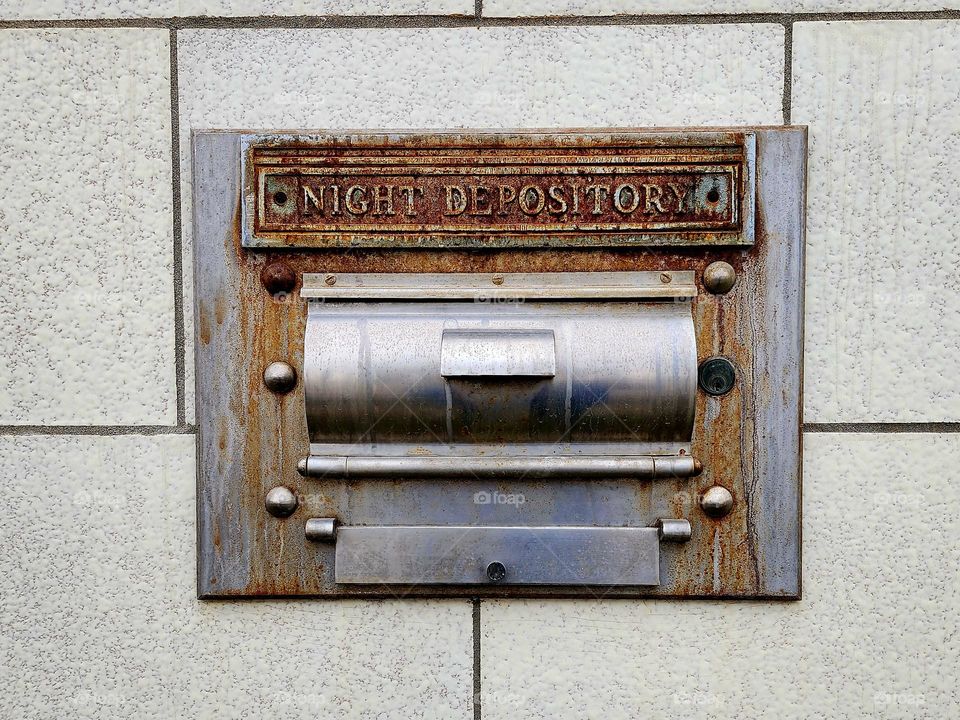 A old bank has been transformed into a modern business in a downtown business area however the original night depository box remains