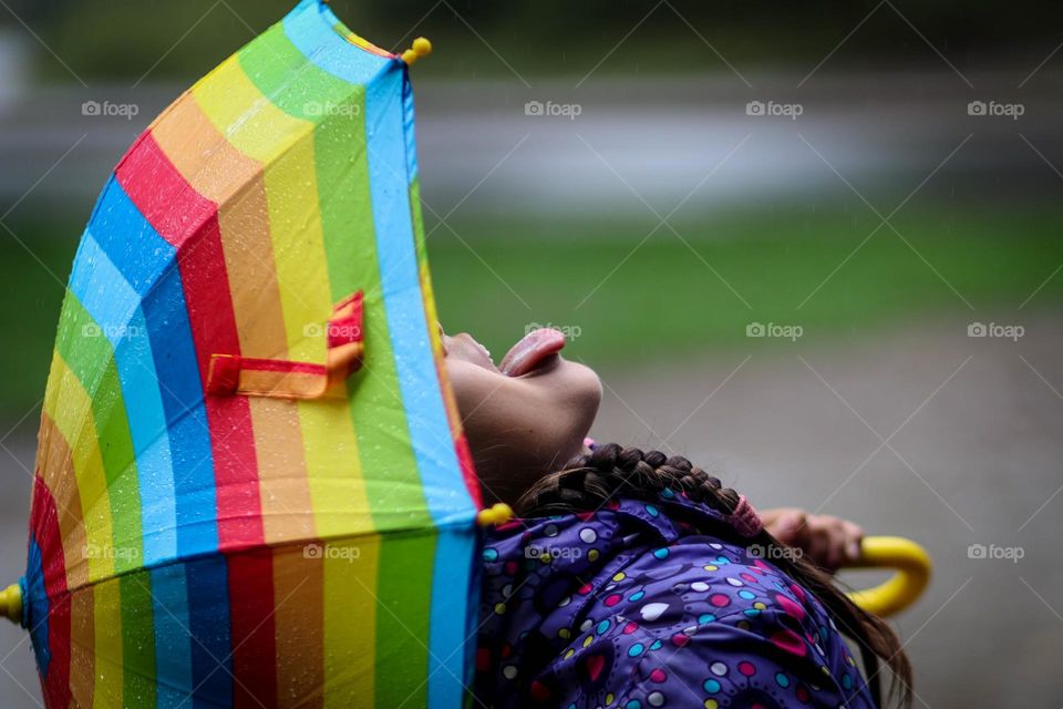 Cute little girl is catching raindrops in her mouth