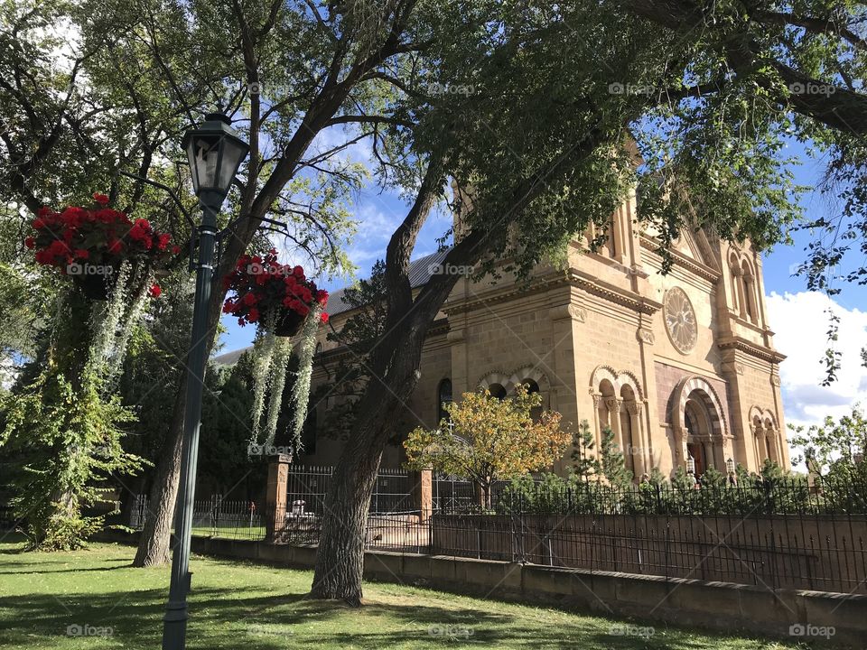 Santa Fe Cathedral from an adjacent park in early evening light, lamppost with flowers