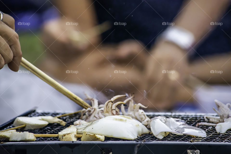 Fresh squid and mushrooms on the grill grate steel.