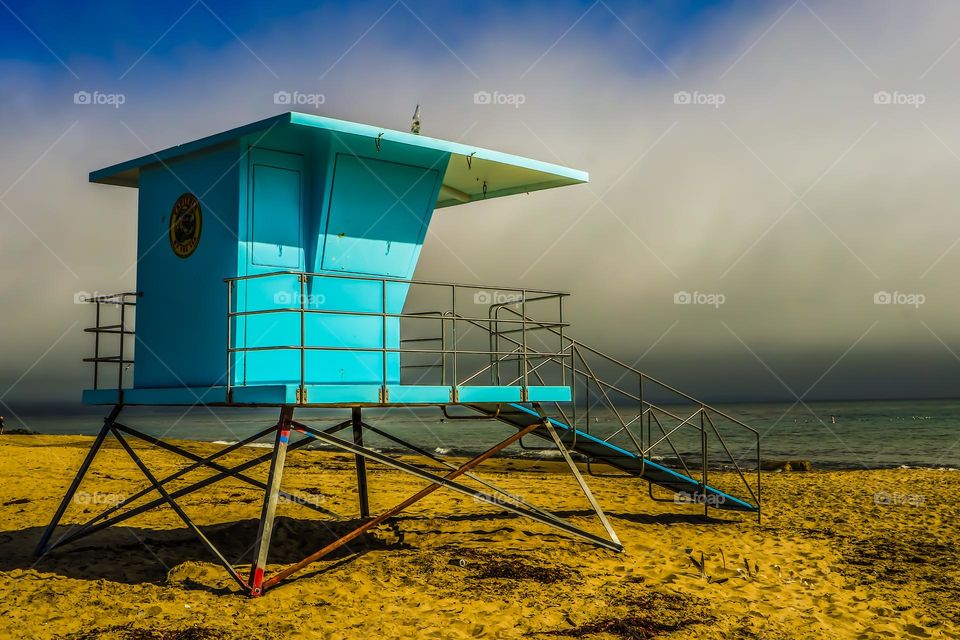 Blue lifeguard stand majestically sitting on the beach in Capitola California on a foggy cloudy afternoon 