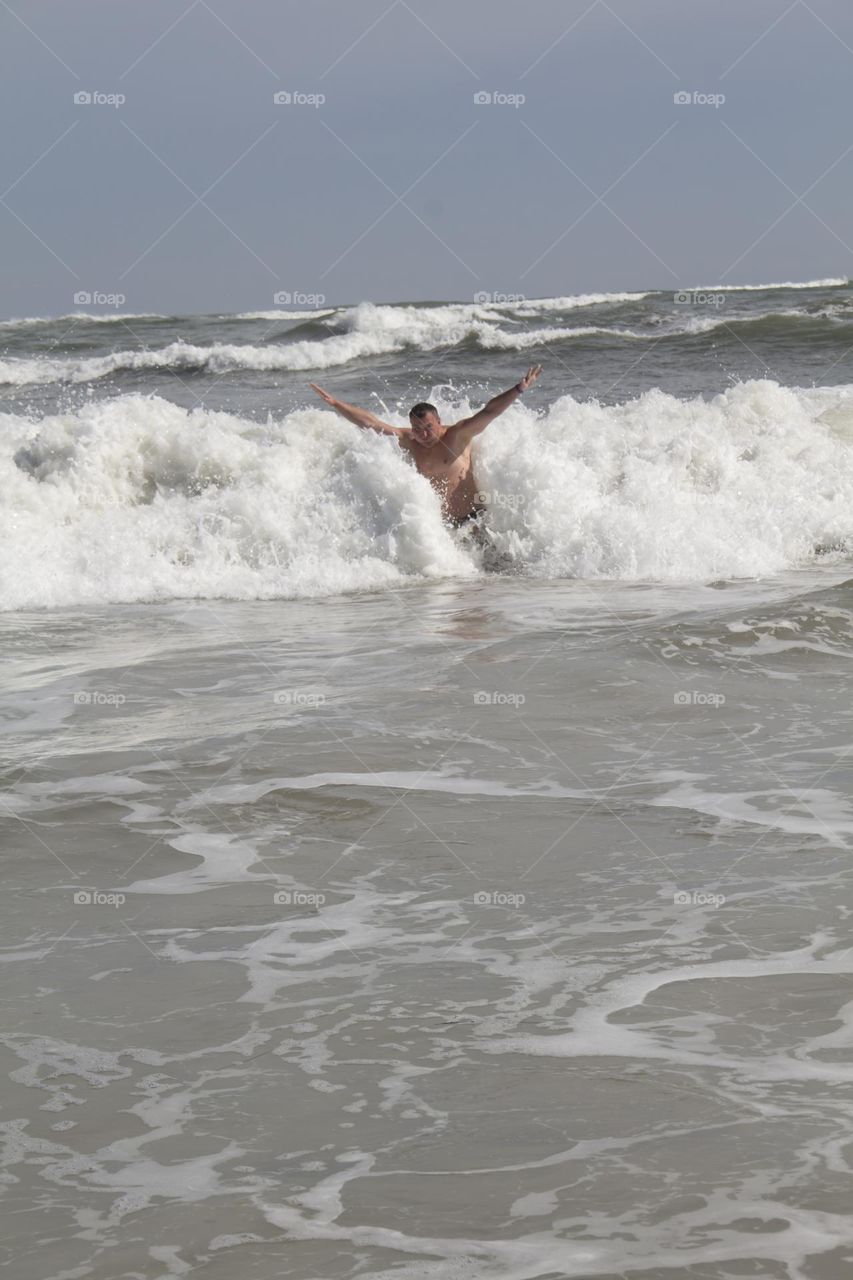 A man swims on big waves with white foam on the sea.