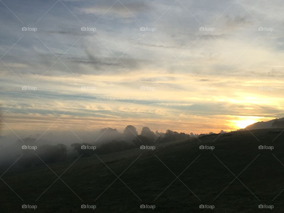 Misty morning with sun coming up over Bredon Hill in Worcestershire 
