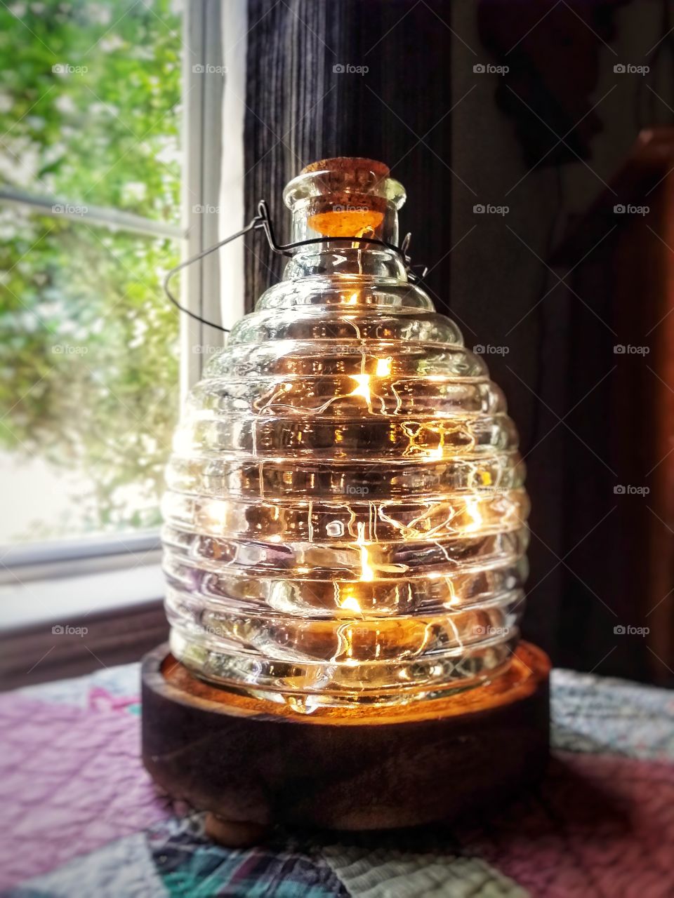 The natural light thru a window and the artificial light of small lights in a lamp made from an old honey jar