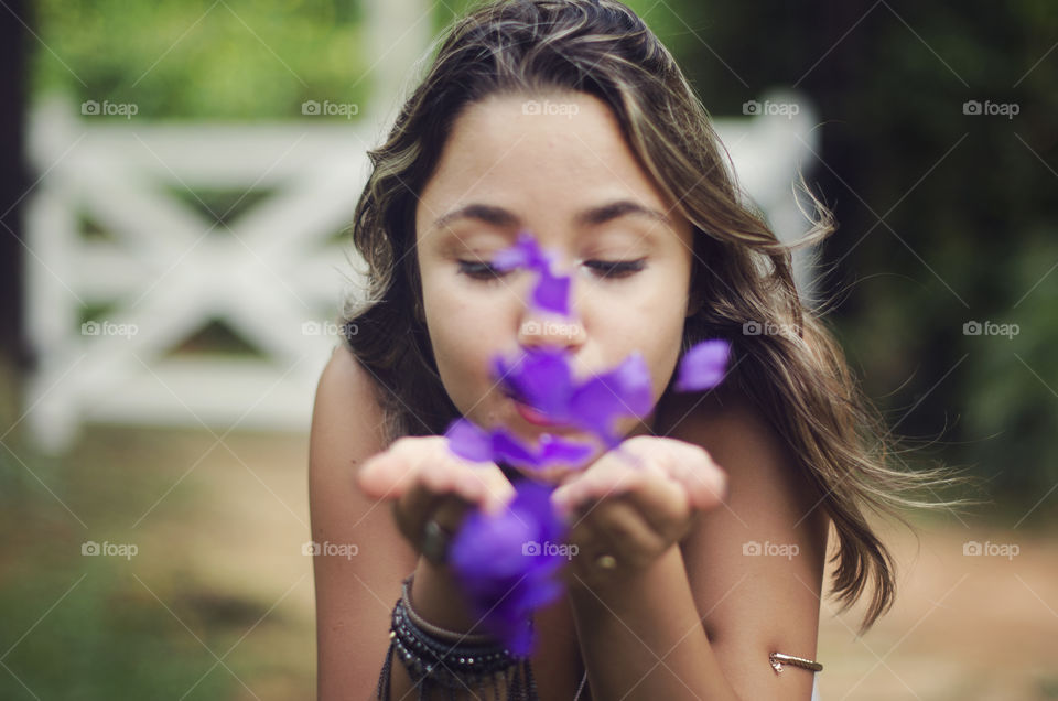 Teenage girl blowing flower petals
