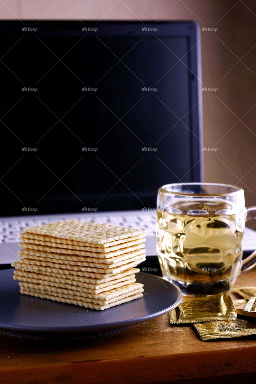 soda crackers, cup of tea and laptop computer