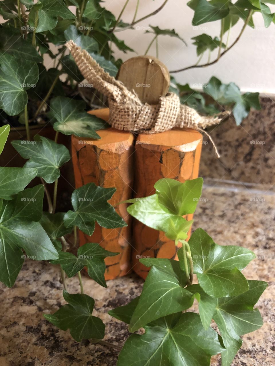 Wood carved pumpkin decoration for Fall with English Ivy plant on counter top 