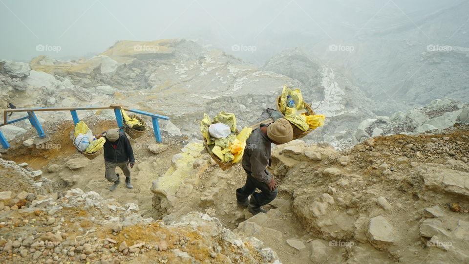 Traditional sulfur miner in Ijen crater, Banyuwangi, East Java Indonesia. They bring the sulfur from the crater valley for earning 10 usd for one trip.