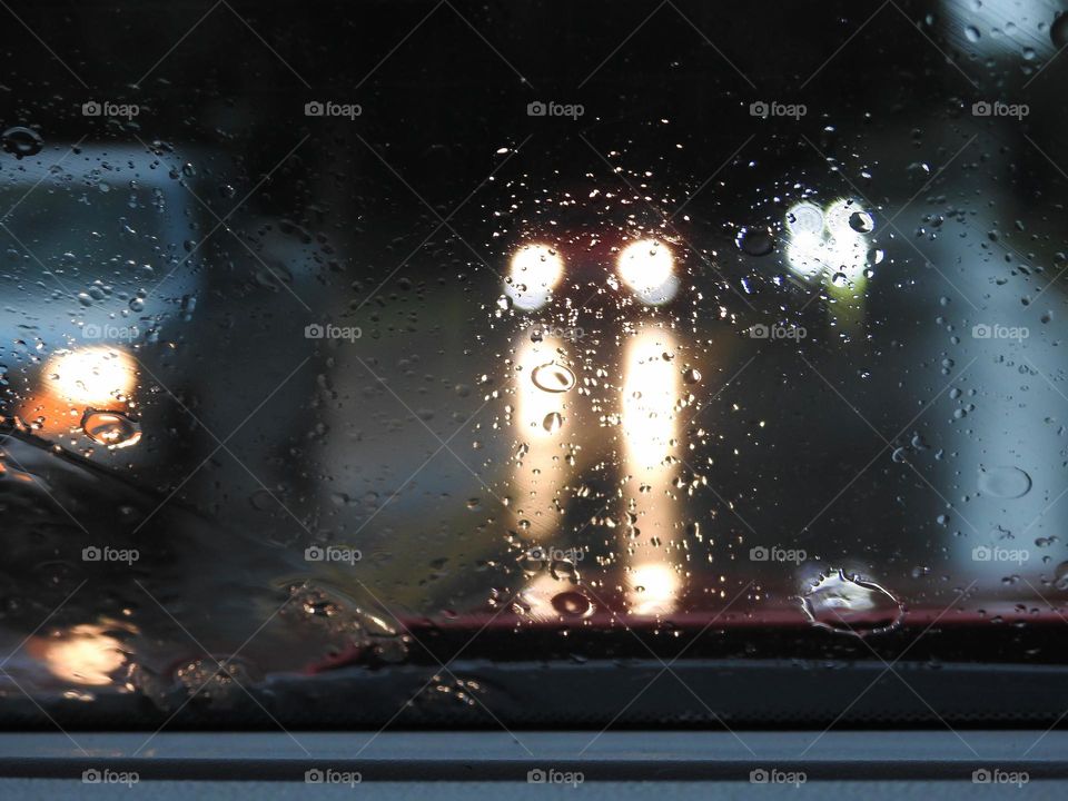 Commuting: cars driving on the opposite direction from the pickup truck driving while it’s raining with the lights on.