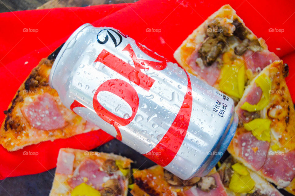 A can of diet Coke with a red background and pizza