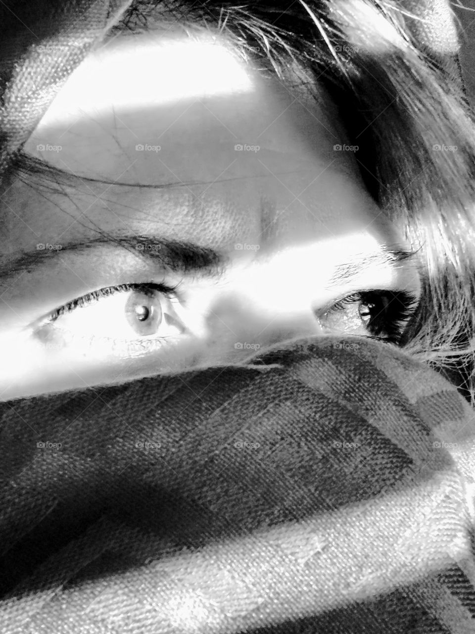 Sunlight and shadows on a face partially covered by a scarf