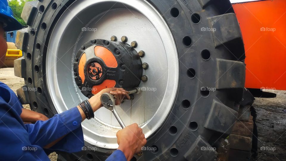 A worker is doing wheel bolt tightening activities.