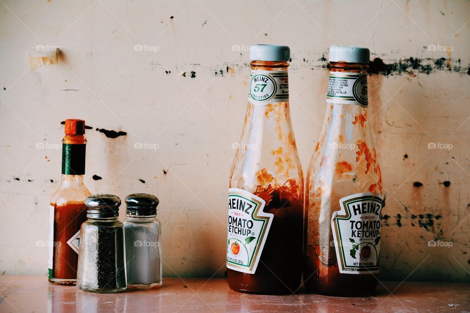 still life restaurant diner modern shot of messy glass ketchup bottles and salt and pepper and tabasco sauce on a grimy table with firstly aesthetic vintage retro 