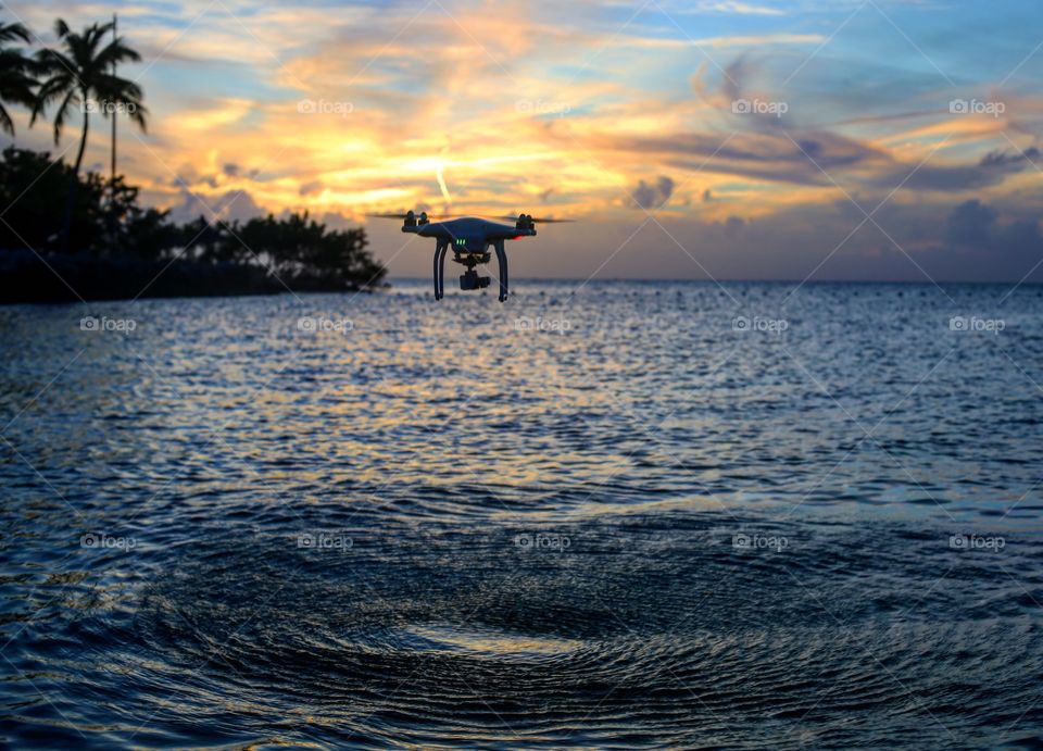 Drone flying over the ocean during sunset