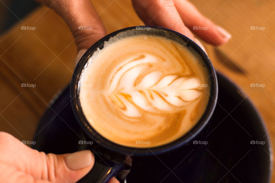 Hands holding coffee with latte art