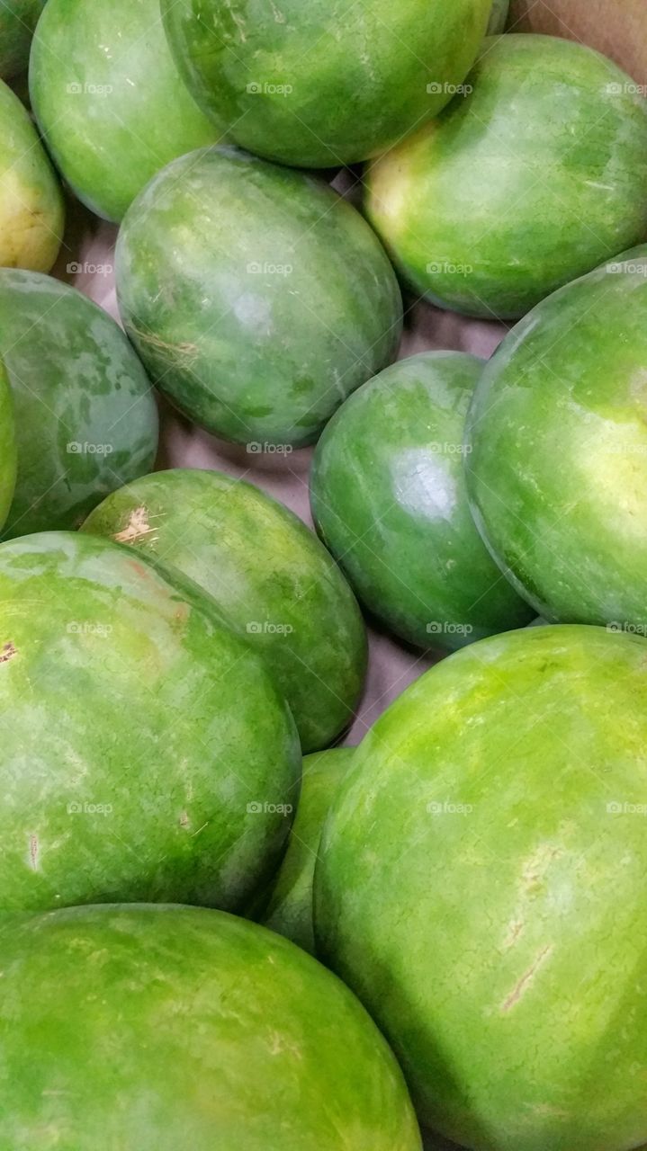 Whole watermelons for sale in a local market. These are piled together for passing customers to select.