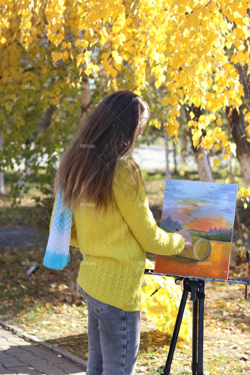 девочка в свитере рисует в парке