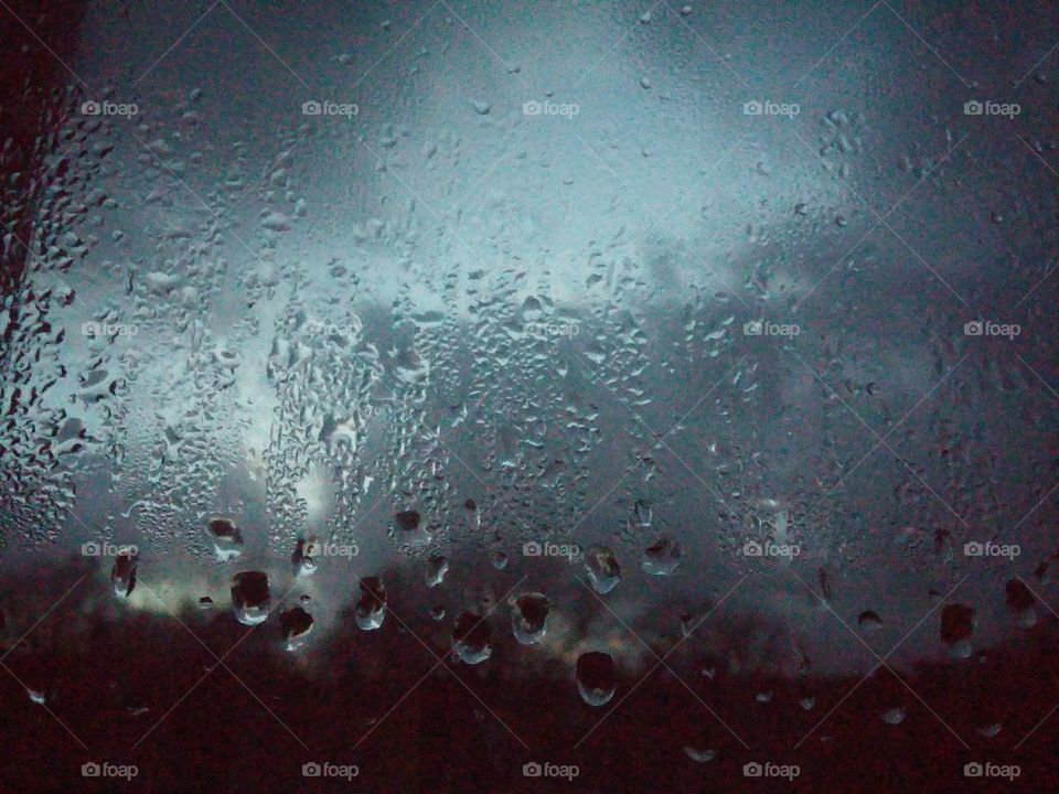 rain on window with storm clouds in the background