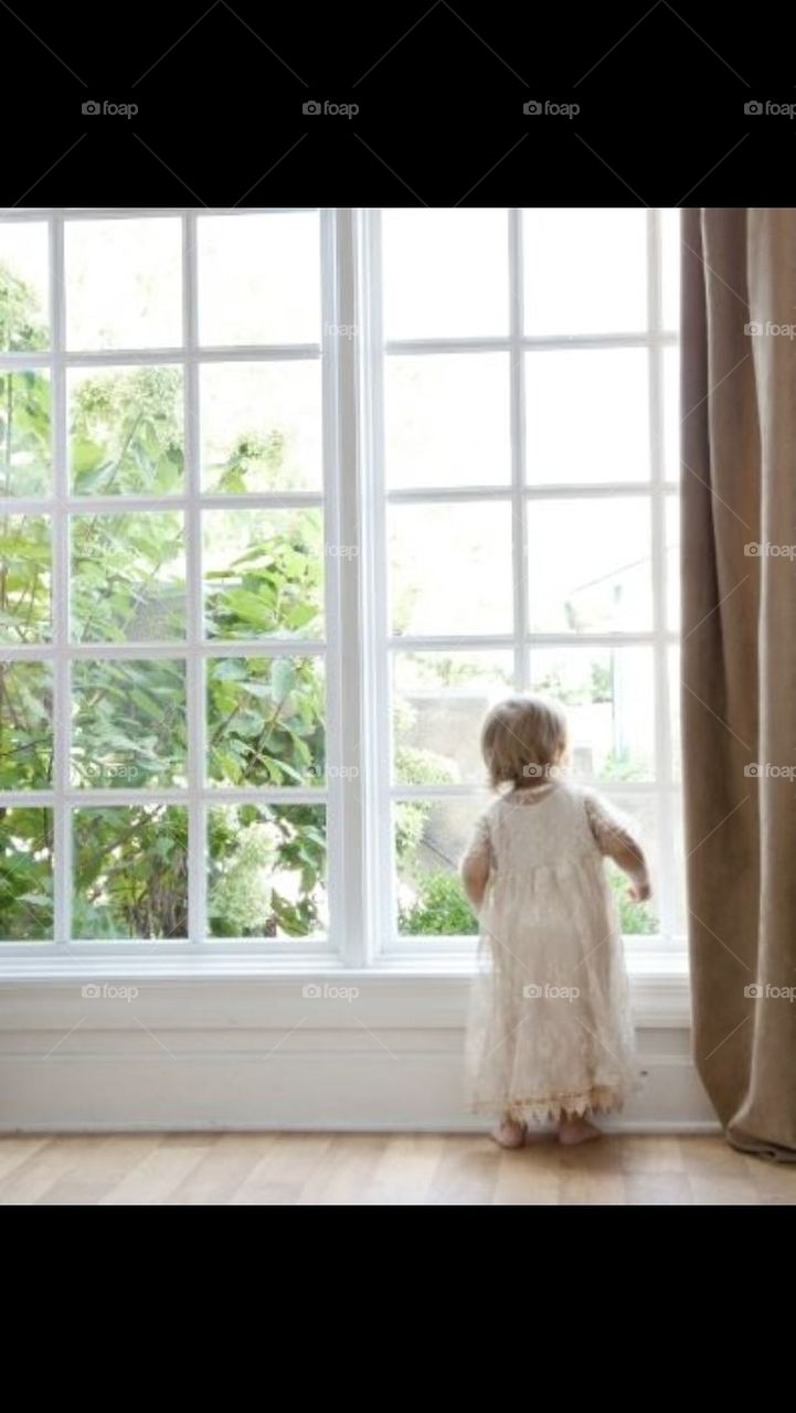 Little Girl in lace dress looking out of the window