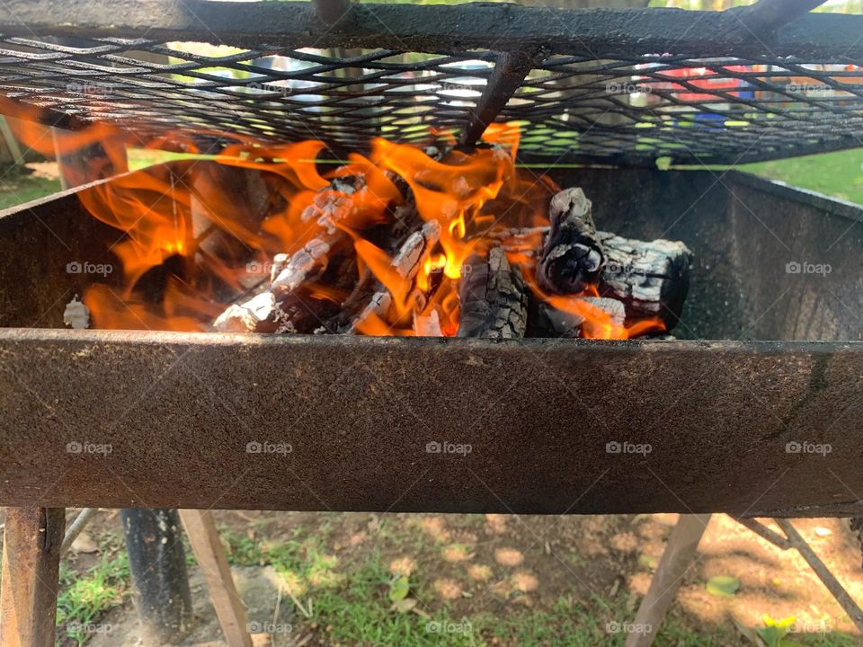 Ready for a barbecue on a sunny day. Flames, smoke, iron grill 