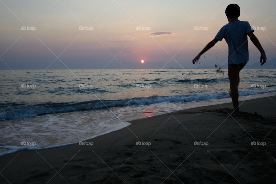 child playing on the beach at sunset