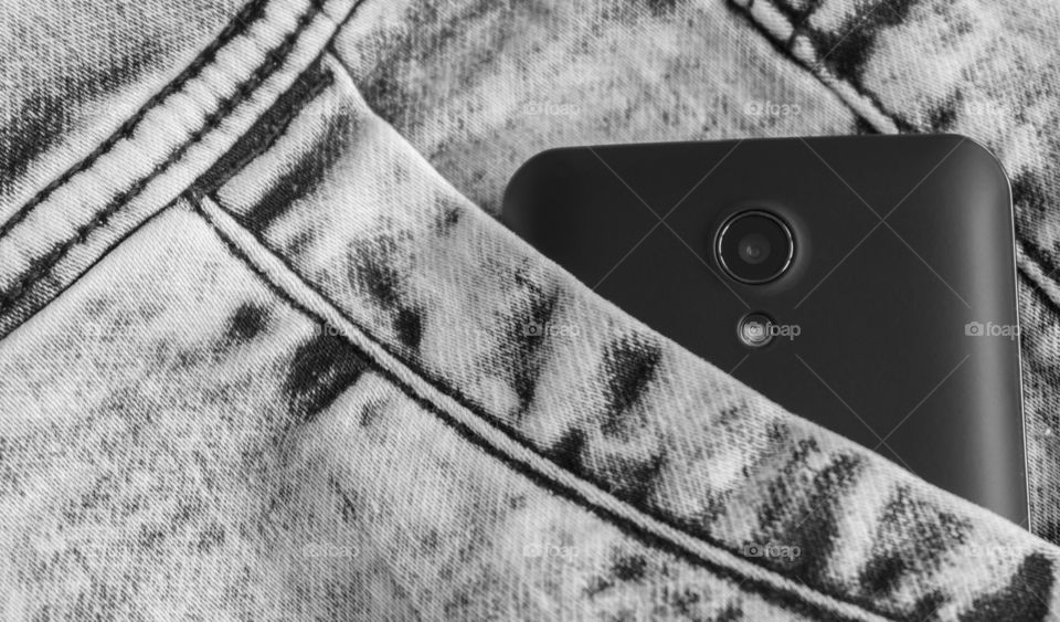 Black smartphone in jeans pocket.Cell phone camera close up