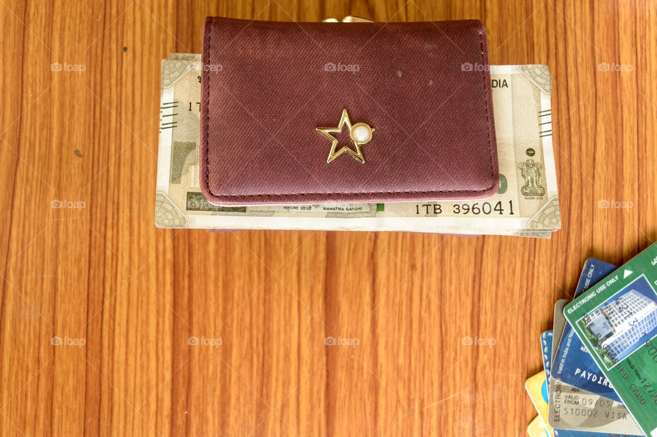 Five hundred (500) cash note in brown ladies purse and stack of credit cards on a wooden table. Business finance economy concept. High angel view with copy space room for text on front of image.