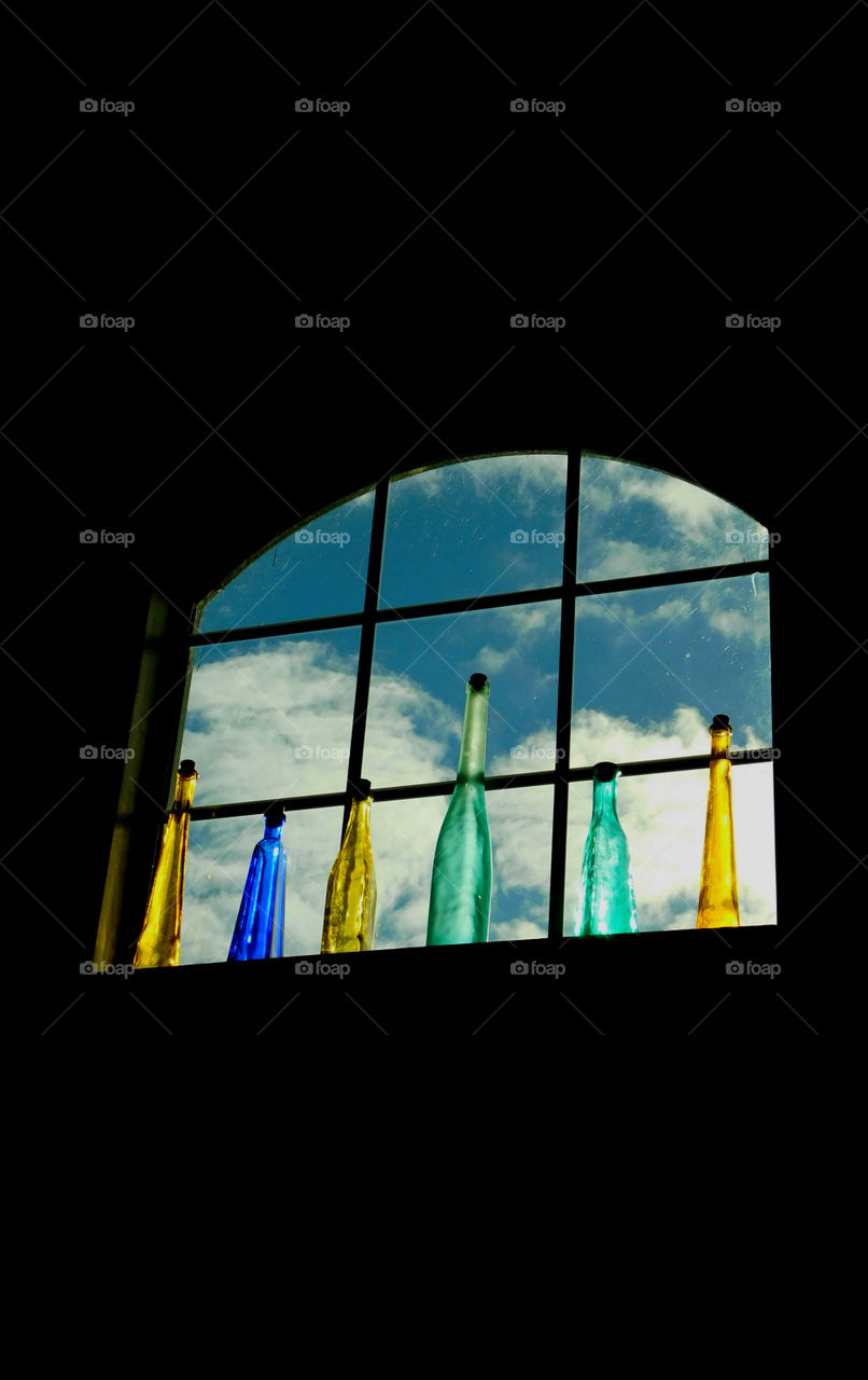 View from within! 
A photo of a puffy clouded blue sky and colorful bottles sitting on my window sill!