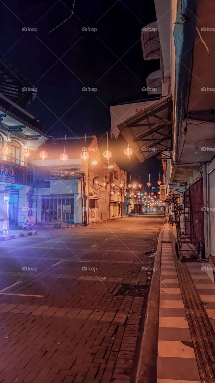 Portrait of a quiet city street at night with hanging lights burning, creating a calm and peaceful atmosphere