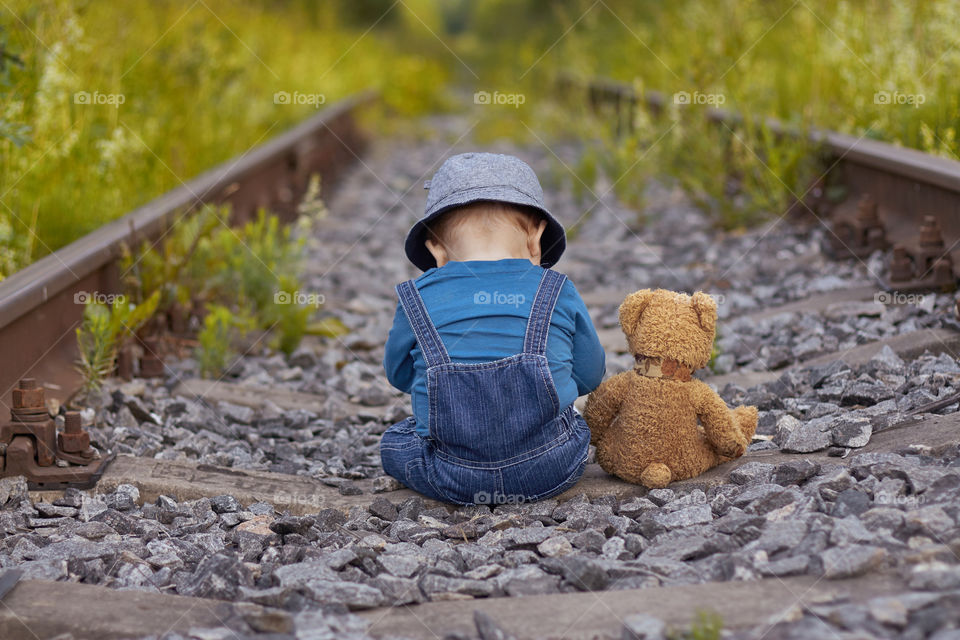 boy sits with a teddy bear on an abandoned railway in the Vologda region