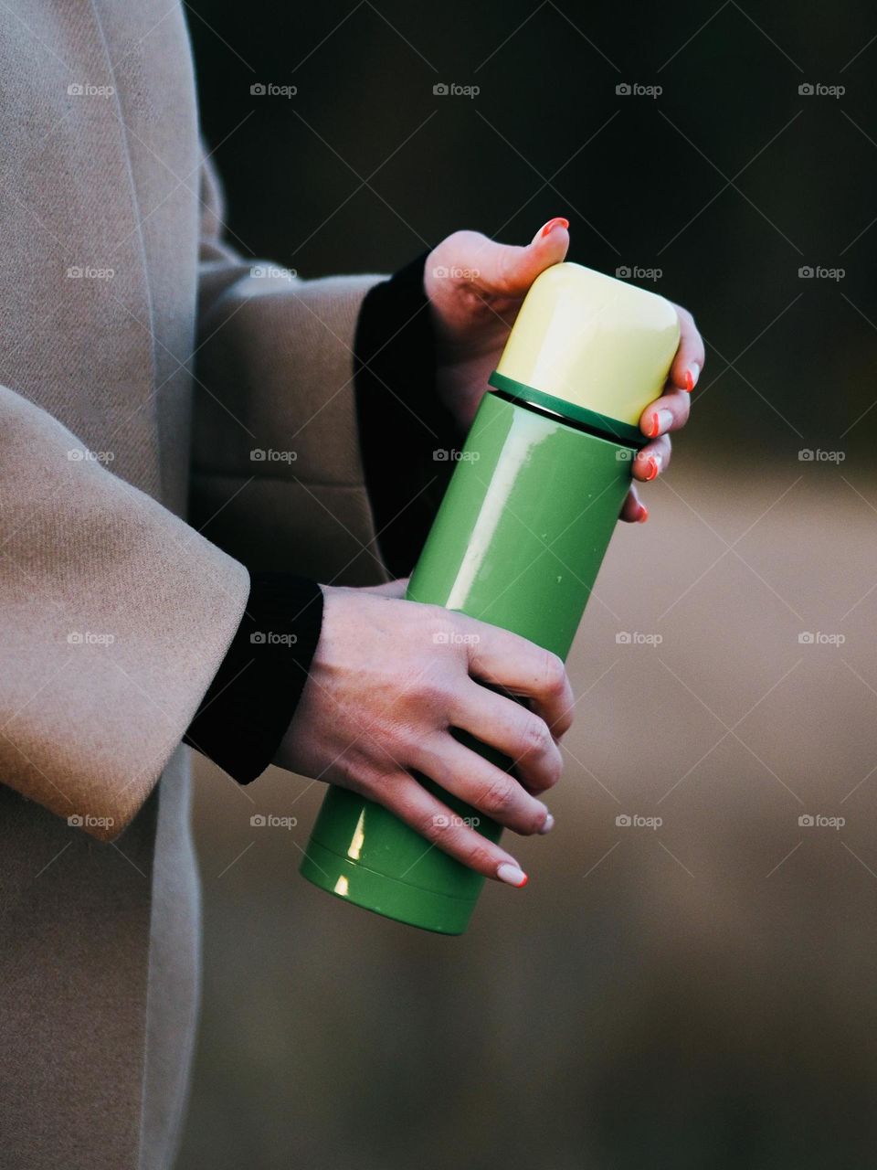 Unrecognisable woman holding a green thermos in her hands