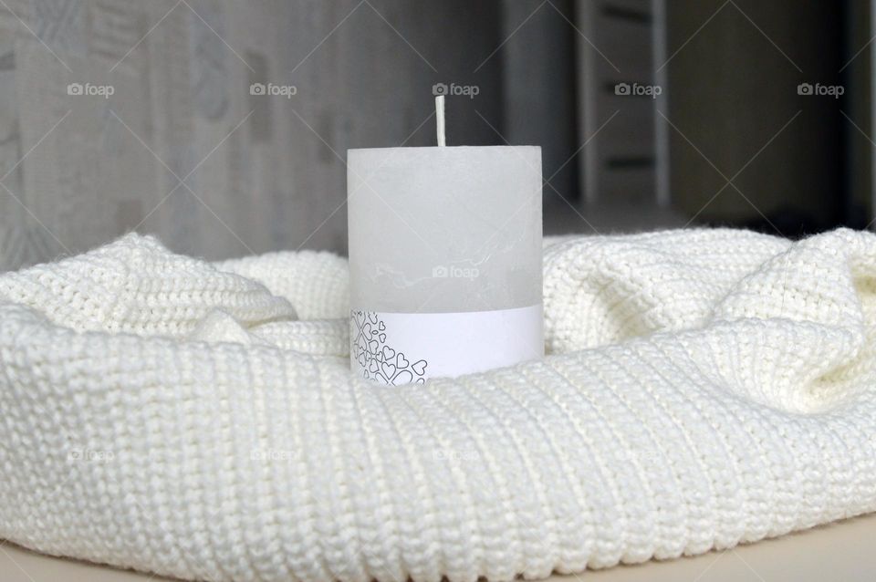 White candle on a knitted background