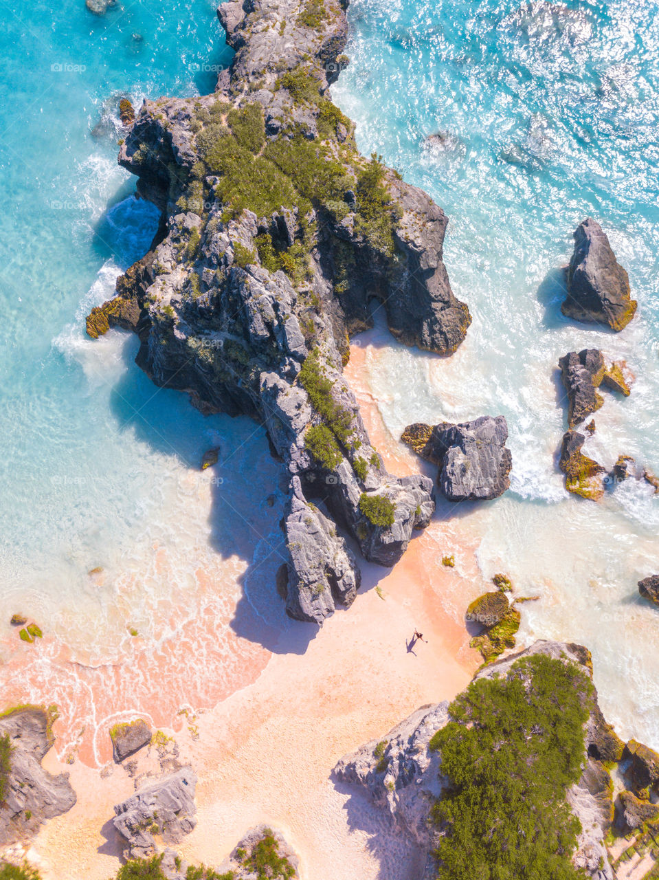 Top down perspective, showing the scale of a beautiful rocky tropical beach with a tiny person