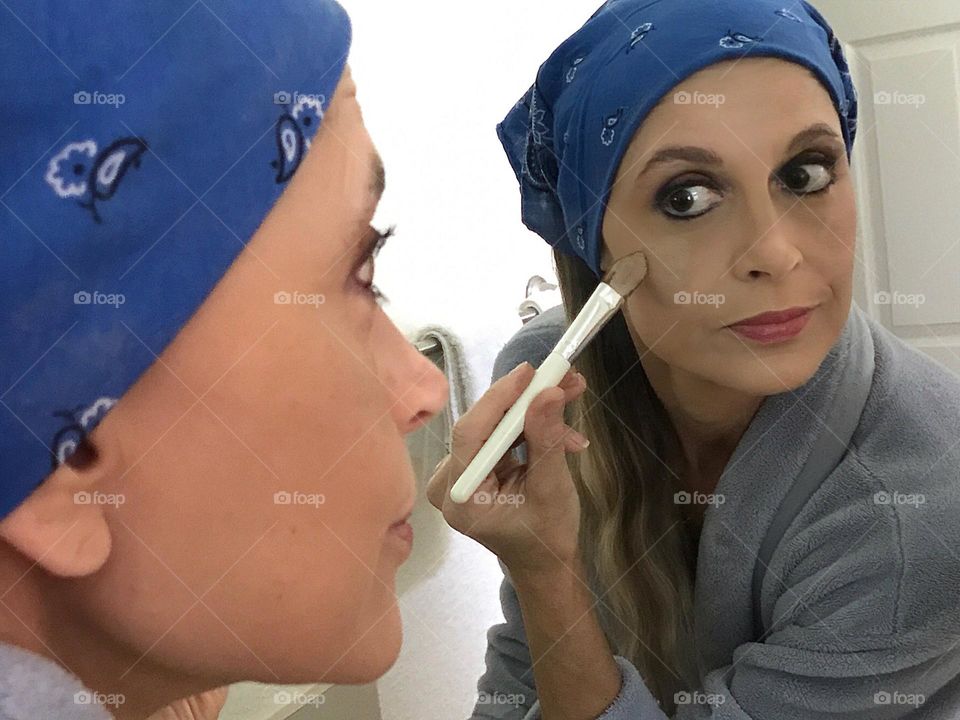 Woman applying foundation while using a mirror.