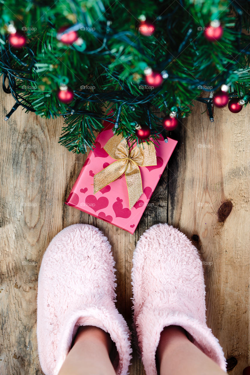 Child looking down at present under Christmas tree