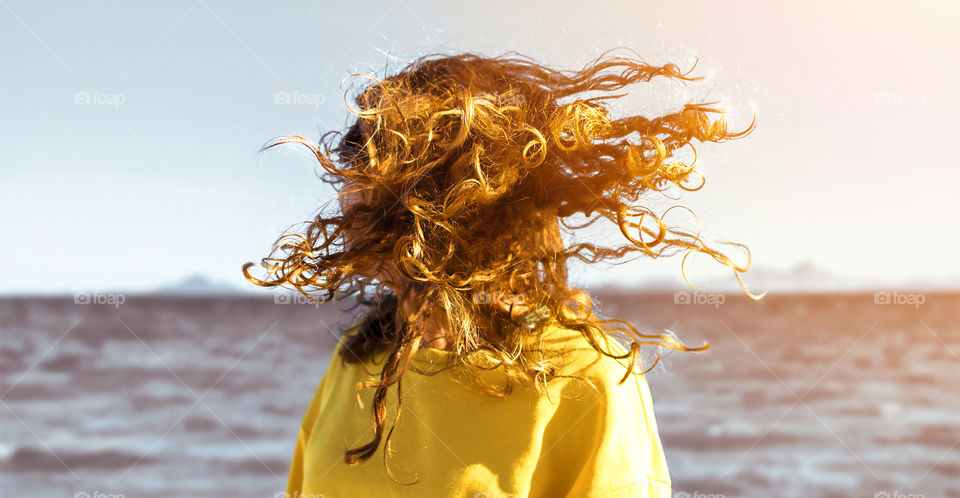 curly blonde hair stopped in motion against seascape at sunset