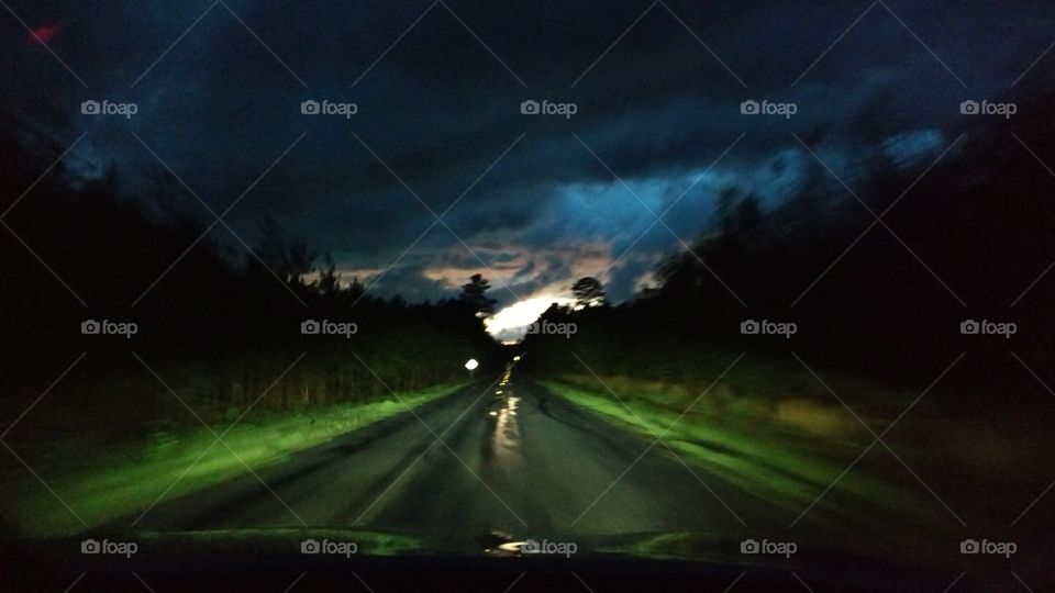 South Carolina road at night after a thunder storm. wicket dark clouds and bright green grass along the side of the wet road shown by headlights