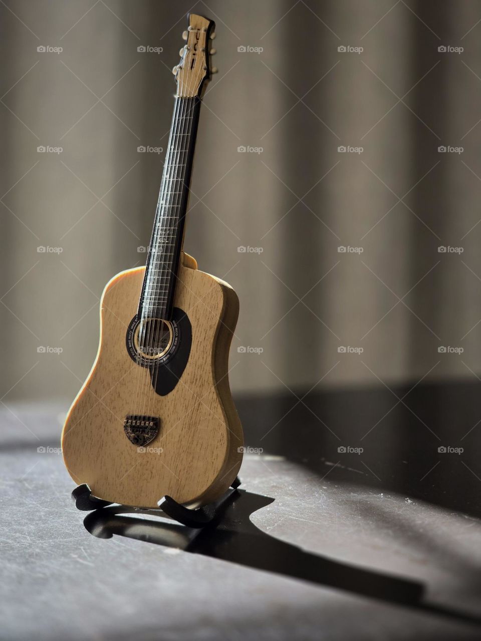 Small collection guitar placed on a table while receiving sunlight from the window.