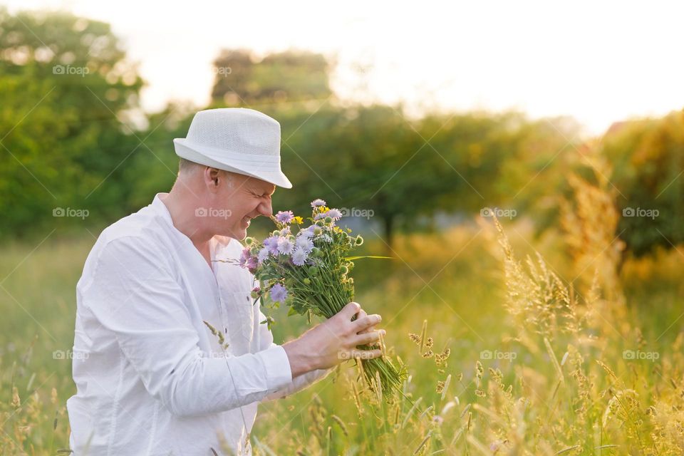 A nice man with a bouquet of wildflowers. Sunset on a field of flowers