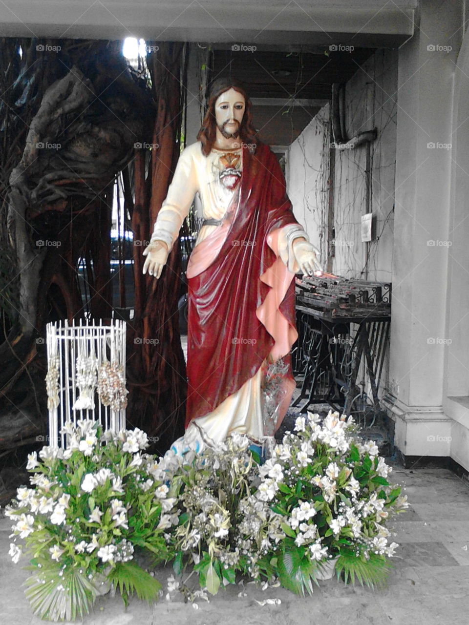 sculpture of jesus christ on the church with flowers on his knees