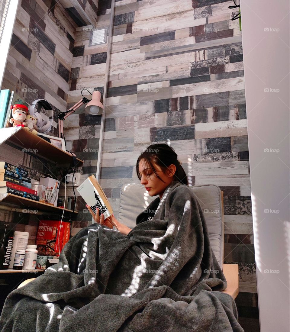 Girl reading in a comfortable chair with a blanket on / favourite place at home / Reading a book at home / space to spend free time