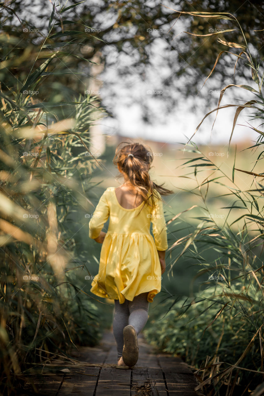 Little girl playing near lake at autumn day 