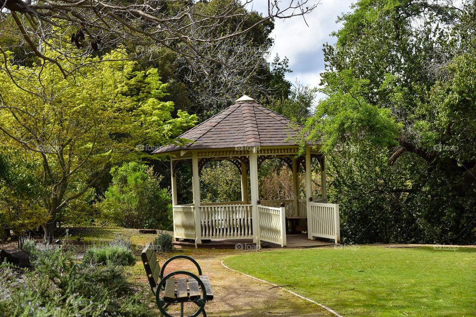 Gazebo surrounded by trees and plants in a park.