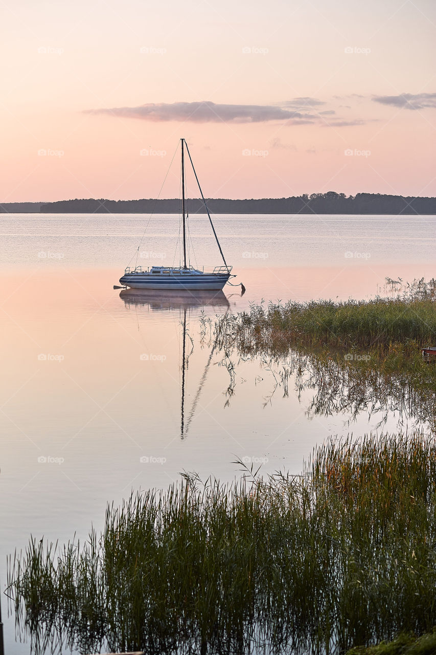 Yacht moored near a harbour in coast at sunrise. Candid people, real moments, authentic situations