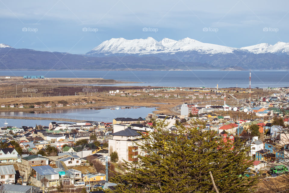 view of the city with lake and snowy mountains at the back