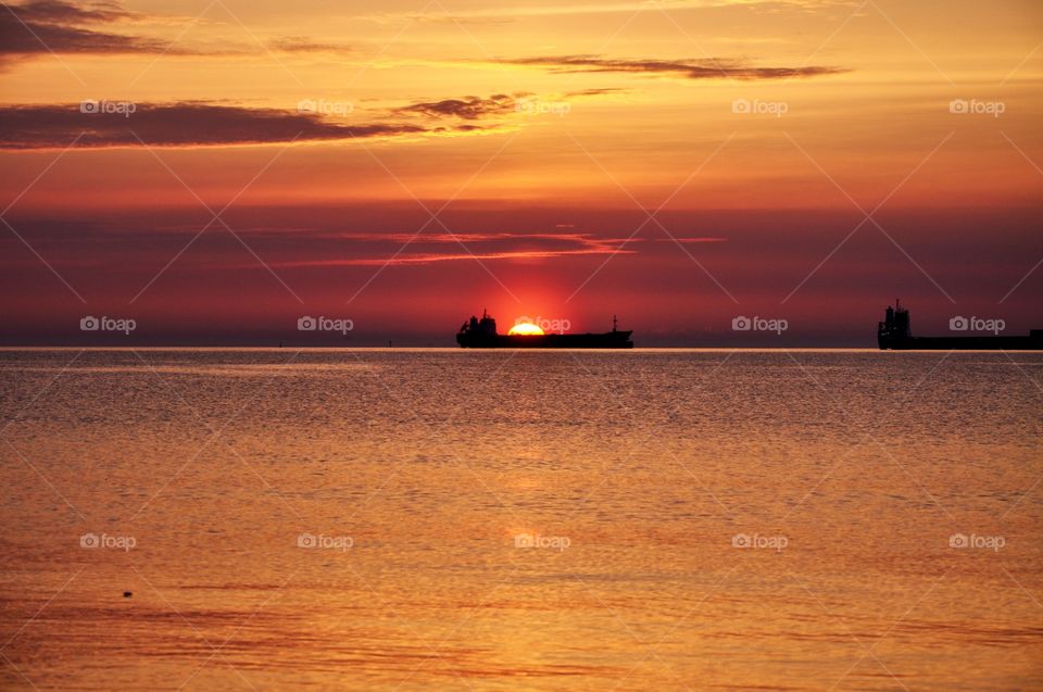 Beautiful bright sunrise over the Baltic in Gdynia, Poland - shops on horizon, silhouettes and calmness 