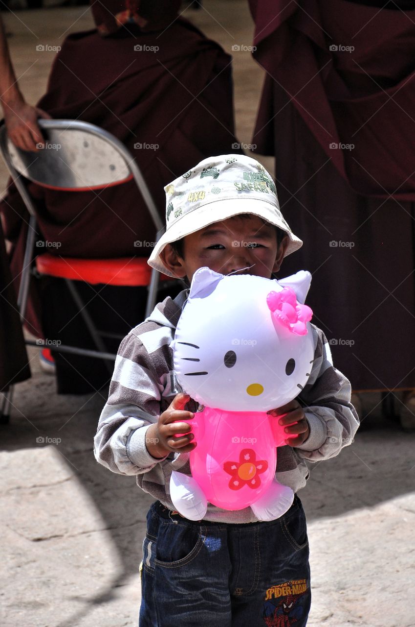 cute boy with colorful kitty balloon in the yard of shigatse monastery in tibet