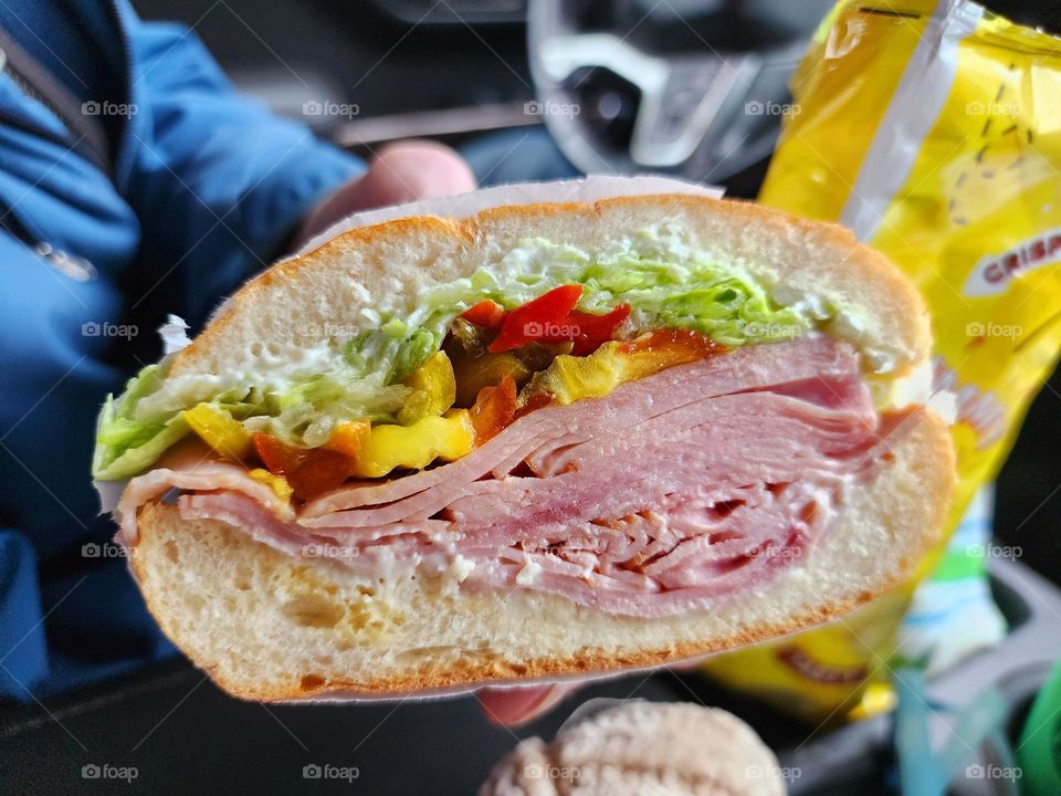 Large deli sandwich sliced to reveal ham, lettuce, and peppers