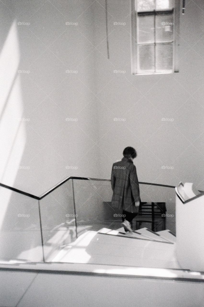 Woman walking down the stairs in the Drents Museum Assen, Netherlands. Black and white, analog picture.