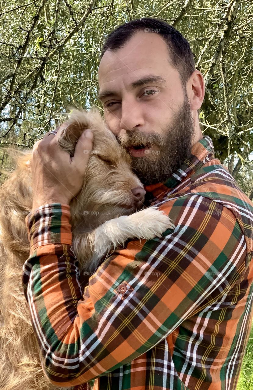 Man cuddles terrier dog in his arms